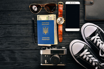 Travel, camera, sneakers, US dollars, Passport of a citizen of ukraine, phone, watches. Top view. Free space for text.