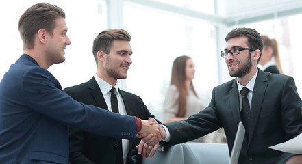 Partners concluding deal and shaking hands in the presence of team members