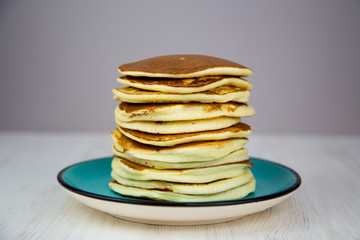 breakfast stack of puffy pancakes on a turquoise plate
