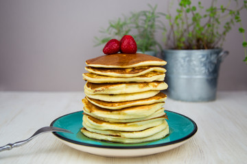 A stack of american pancakes with maple syrup and strawberries on top