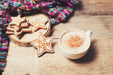 Gingerbread with cup of coffee and cozy scarf on wooden background