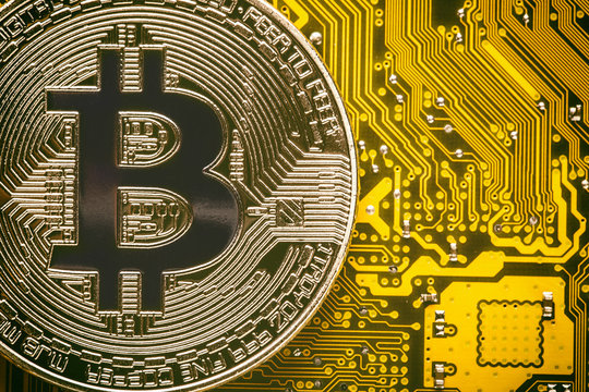 Bitcoin on the yellow computer circuit motherboard close up. Cryptocurrency virtual money background.