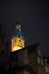 View of the Main Town Hall's lit tower and other old buildings in the Main Town (Old Town) in Gdansk, Poland, in the evening. 