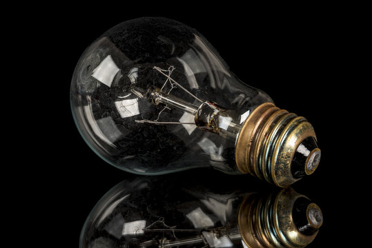 Single old light bulb on a black surface