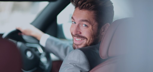 Fototapeta premium Portrait of an handsome smiling business man driving his car
