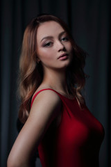 Charming brunette in a red dress posing on a black background.