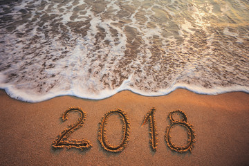 Happy New Year 2018 concept, lettering on the beach. Sea sunrise