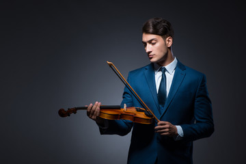 Young man playing violin in dark room