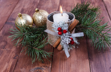 Hot white candle  and a Christmas ball on a wooden background