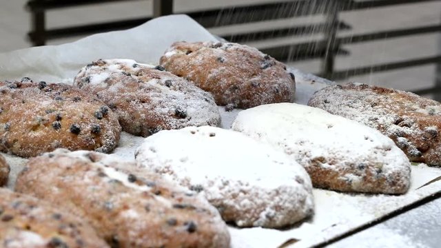 baker covers an German Christmas raisins Stollen with Icing Sugar