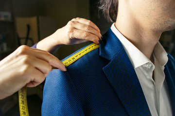Close up of tailor's hands measuring man in blue jacket