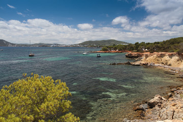 Rocky beach in Ibiza. View of the yacht