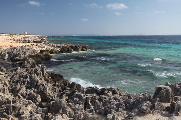 Salinas rocky beach on Ibiza. In the distance Torre de ses Portes and Formentera island.