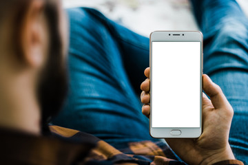 Young bearded hipster holding a white smartphone in the hands of a white screen, holding mobile...