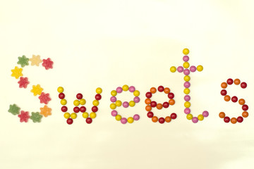 A word Sweets lined with candies on a light background
