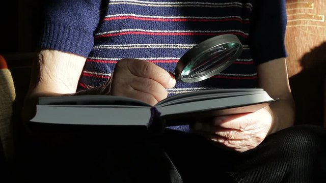 Grandmother reading a book with a magnifying glass