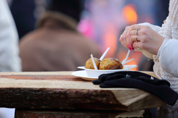 Dłonie kobiety w czasie jedzenia pieczonych ziemniaków na zewnątrz. - obrazy, fototapety, plakaty