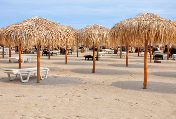 sandy beach with thatched umbrellas and sunbeds for your design