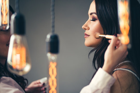 Professional makeup artist working with beautiful young woman