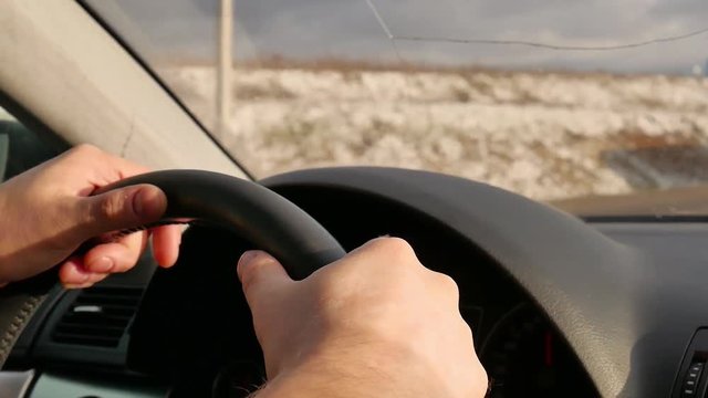 Man's hands holding steering wheel of car