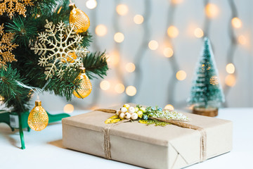 A Christmas tree decorated snowflakes and a garland with gift box on the background of a bokeh and white boards. Merry Christmas, ideas for postcards for winter holidays