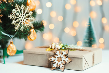 A Christmas tree decorated snowflakes and a garland with gift box on the background of a bokeh and white boards. Merry Christmas, ideas for postcards for winter holidays