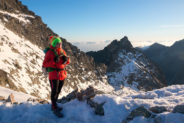 Successful woman backpacker enjoy the view on snow mountain peak. Motivated hiker with backpack looking at beautiful view. Travel, fitness and healthy lifestyle outdoors in nature.