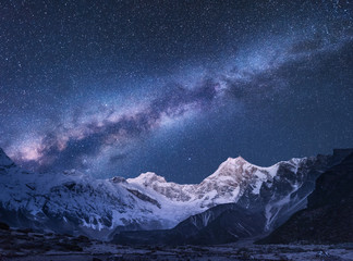 Milky Way and mountains. Amazing scene with himalayan mountains and starry sky at night in Nepal. Rocks with snowy peak and sky with stars. Beautiful Himalayas. Night landscape with bright milky way - obrazy, fototapety, plakaty