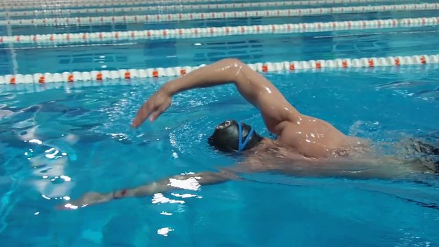 The athlete swims in the pool. A man is swimming with a crawl in the pool.