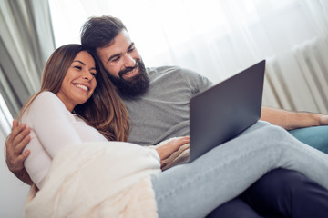 Couple watching a movie on laptop in their living room