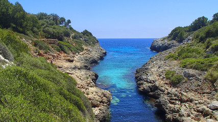 A blue river flows between the rocks and green trees on the coast of Majorca in the Mediterranean Sea © Trebor Eckscher