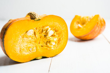 Half of pumpkin with seeds on white wooden background