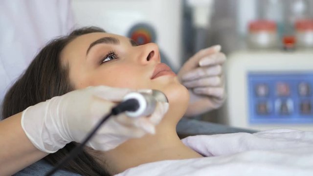 Young woman getting radio frequency lifting procedure in a beauty salon