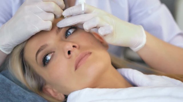 Beautician doing permanent makeup for eyebrows in beauty salon