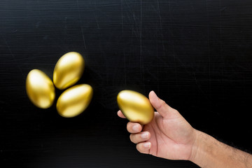 Man holding a golden egg. Golden Egg on black background. Financial success