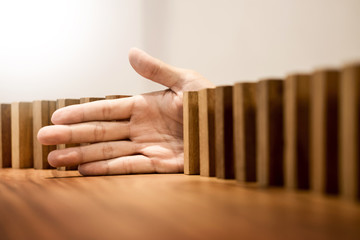 businessman hand stop dominoes continuous toppled or risk with copyspace.