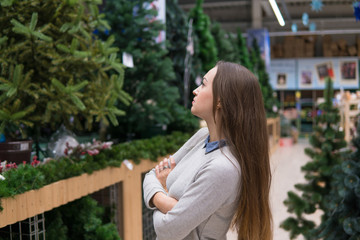 customer girl choosing Christmas tree for the new year on Christmas Eve. difficult decision. Various choice