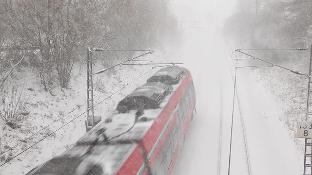 Passenger train passing by during a snowfall in winter
