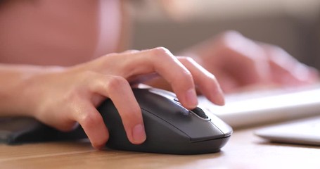Hands typing on computer keyboard and use of mouse in office
