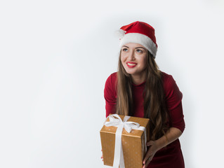 portrait of young christmas woman wearing red santa claus hat giving gift isolated on white background, copy space. She looks happy