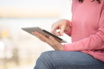Woman typing on a tablet.