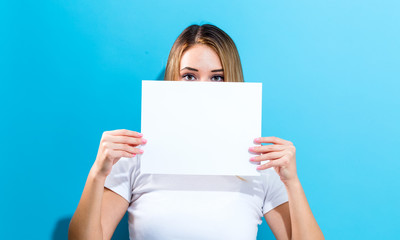 Woman holding a blank sheet of paper in front of her face