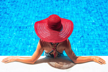 Beautiful european woman in red hat is relaxing in the swimming pool