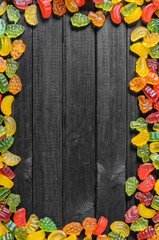 a frame of jelly sweets on a wooden background with free space for text, top view