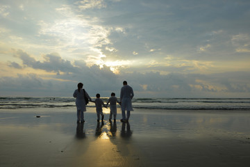 Happy family walking on the beach at sunset