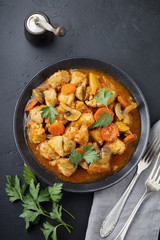 Goulash traditional Hungarian dish. Stew with pepper and tomato sauce in ceramic plate on dark black stone or concrete background. Selective focus. Top view.