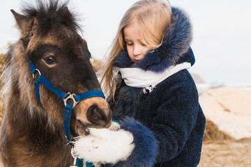 Small girl and small horse in a winter