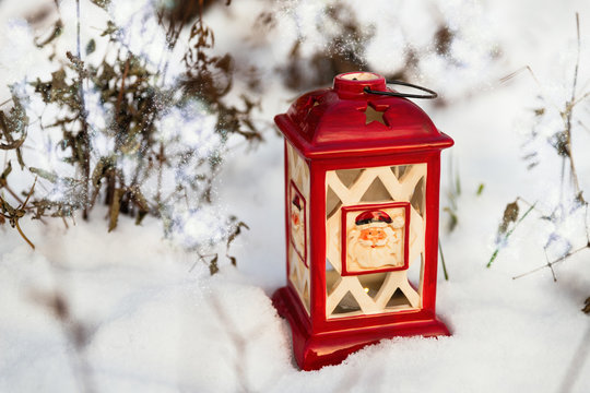 Glowing Christmas lantern settled in the snow. Outdoor Christmas background