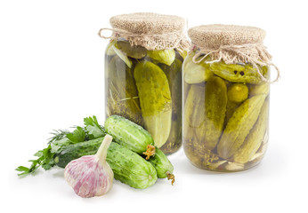 Canned cucumbers in glass jars and fresh cucumbers with herbs
