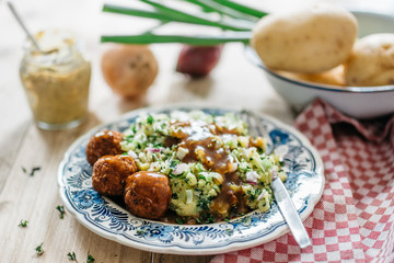 Typical Dutch dish: mashed potatoes with kale, vegan meatballs with gravy, blue plate, nice soft bokeh background, with props